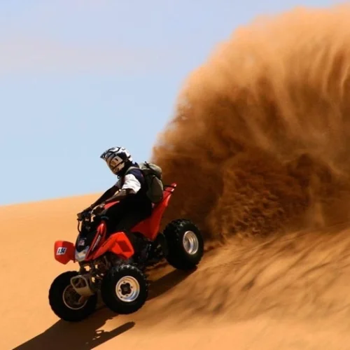 Tourists riding quad bikes across the Dubai desert during an adventure safari