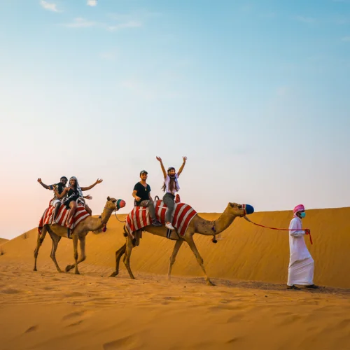 Tourist riding a quad bike over the golden dunes of Dubai